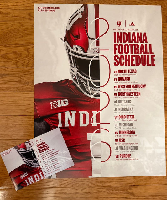 A printed football schedule poster for Indiana University, featuring a large red helmeted football player on a cream background with bold red text listing game opponents. A matching printed card is placed in front on a wood surface.