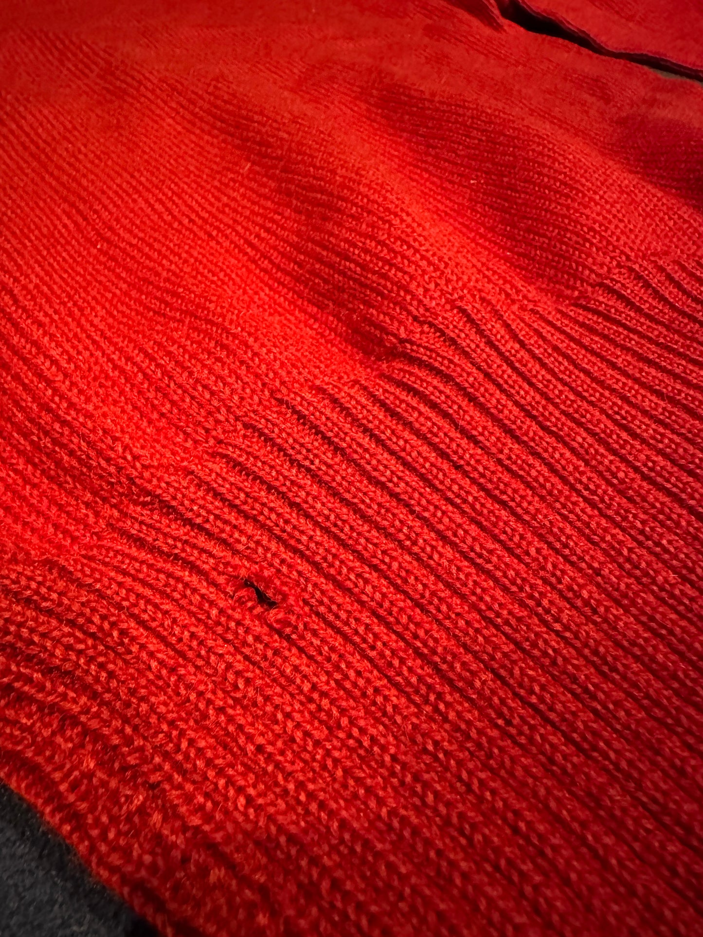 Close up of letter sweater holes and snags.